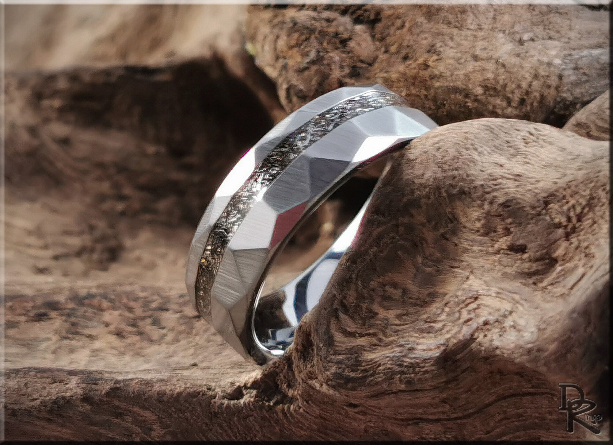 Hammered tungsten carbide ring with meteorite inlay resting on textured wood background