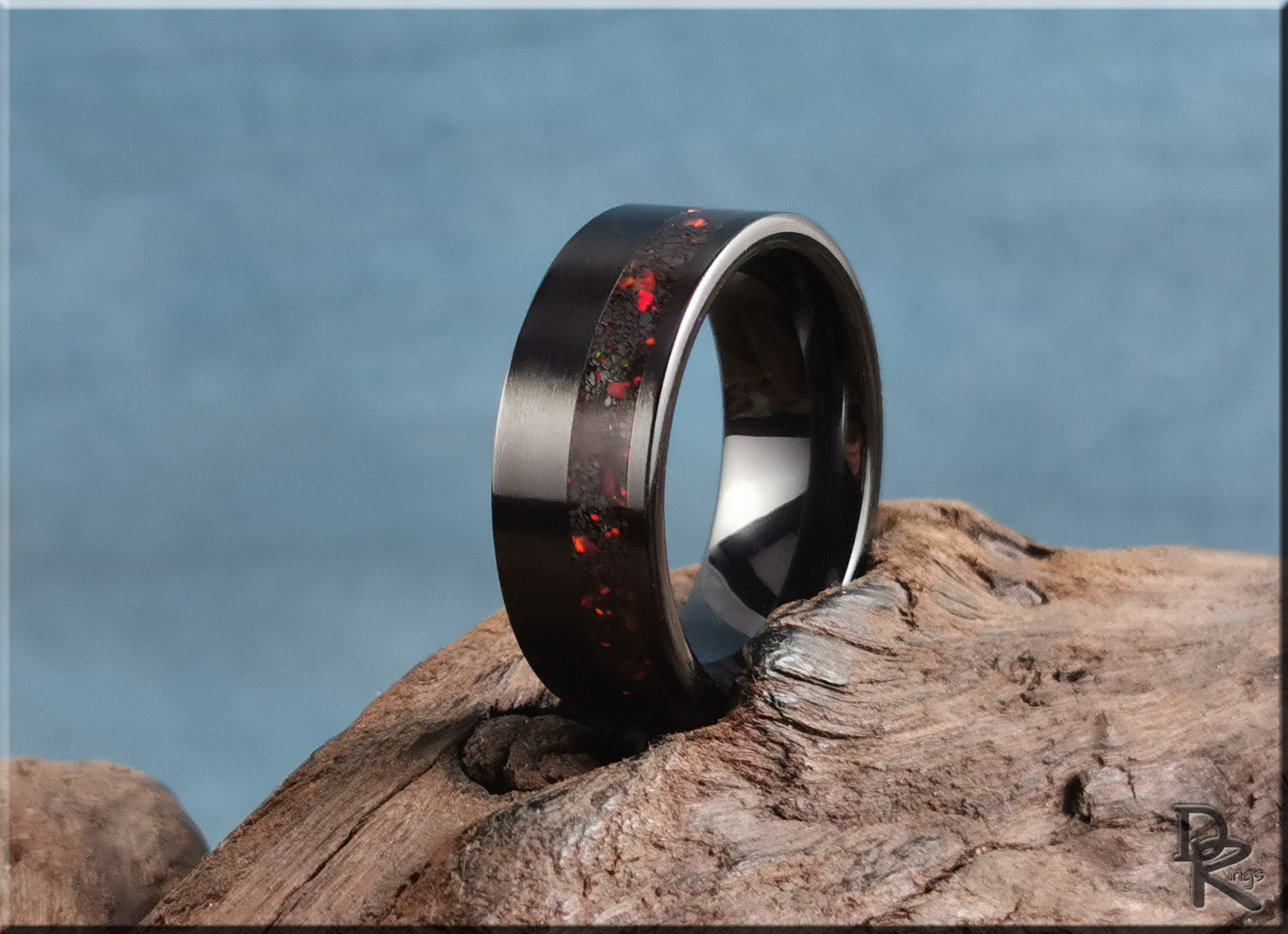 DR Rings black band ring opal with red opal inlay on rustic wood background