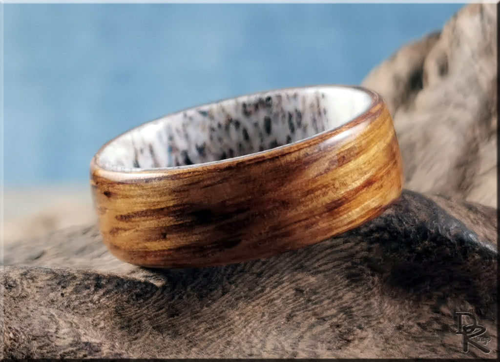 Oak wood ring on antler with smooth polished finish displayed on rustic textured antler piece