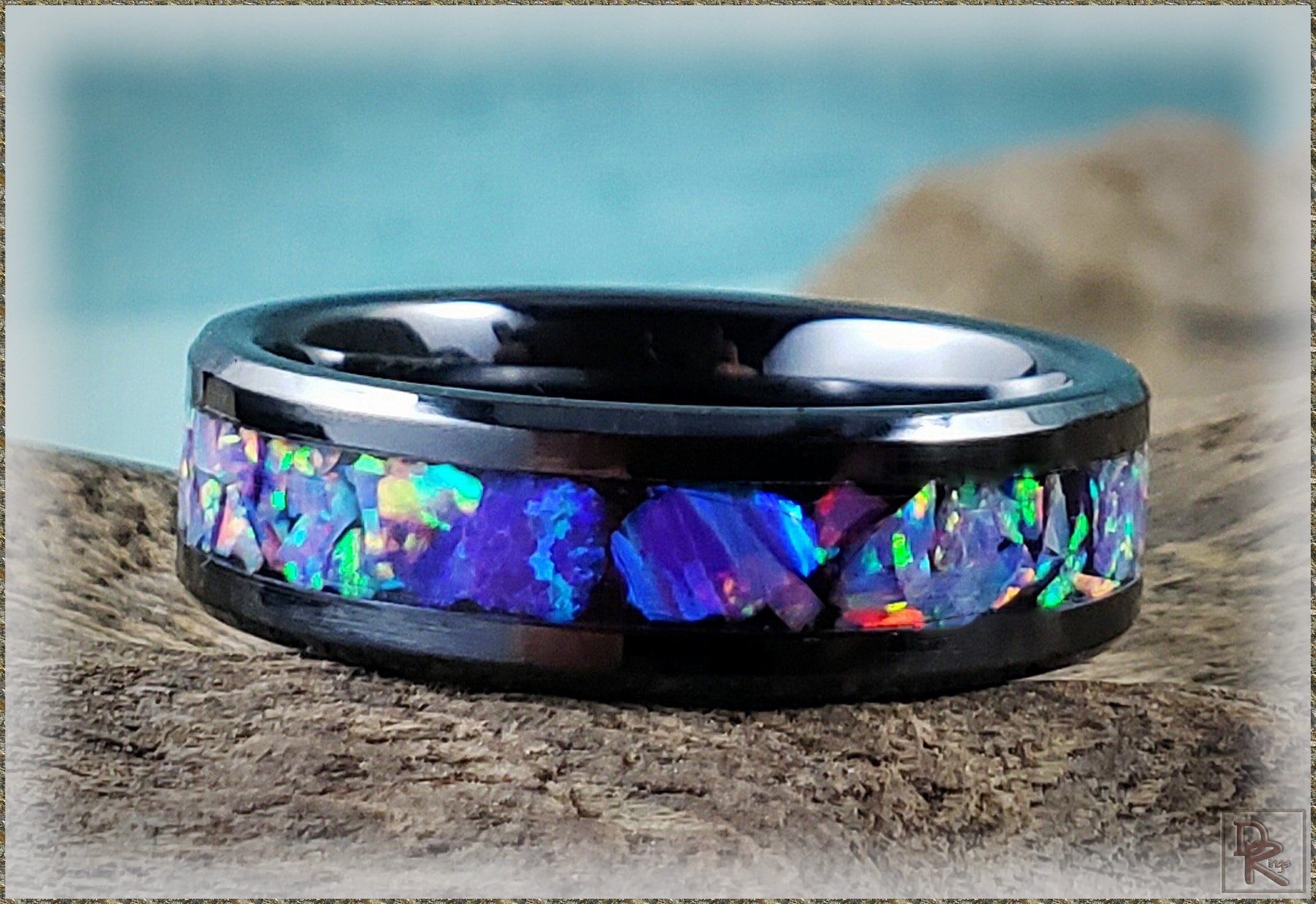 DR Rings black band with vibrant blue and green opal inlay oura ring 4 ceramic style on a textured surface