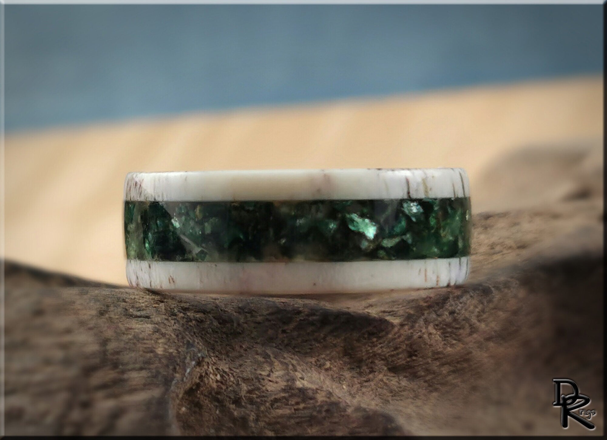 DR Rings antler ring with mica featuring a green inlay set in a white antler band on rustic wood