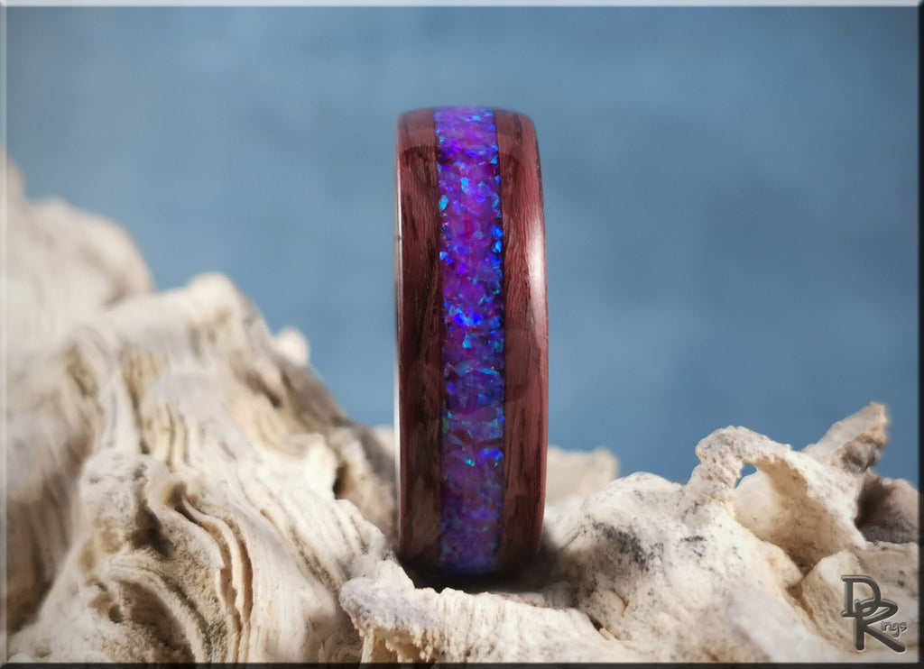 Purpleheart wood ring with opal inlay featuring vibrant blue and purple colors on natural textured background