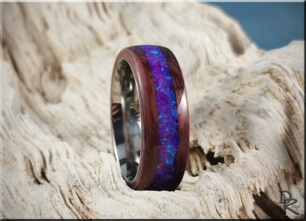 Purpleheart wood ring with opal inlay featuring vibrant blue and purple tones on natural wood background