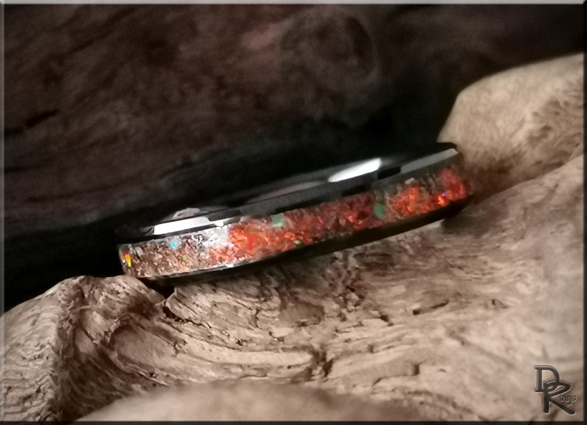 DR Rings ceramic ring with inlay featuring a vibrant red and green stone design on rustic wood background