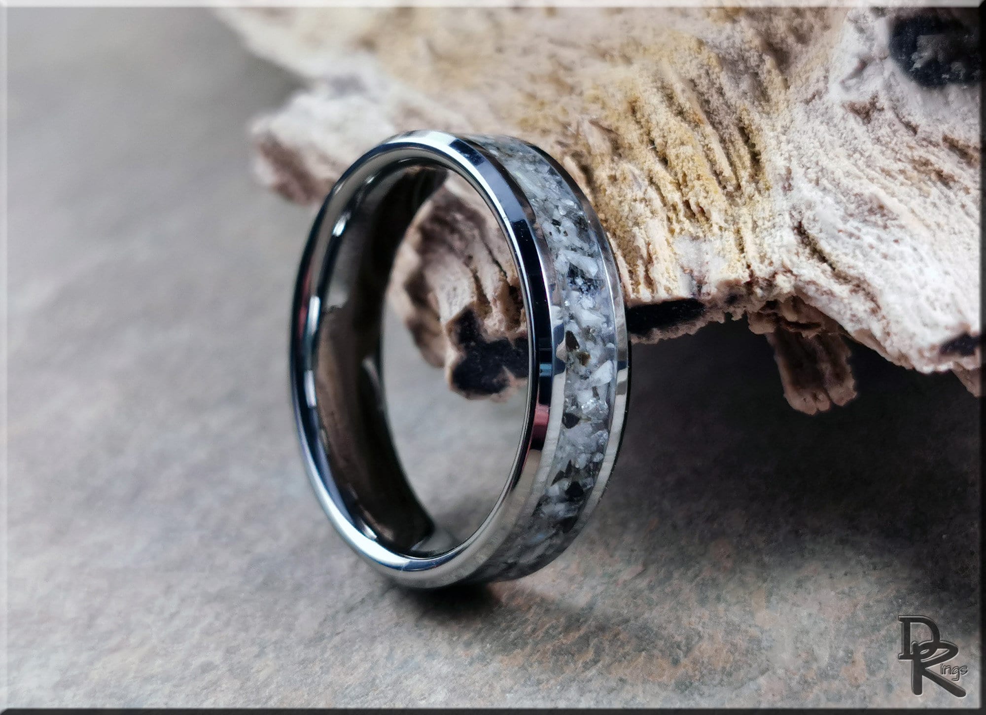 DR Rings tungsten ring with moonstone inlay featuring a polished metallic finish on a textured surface