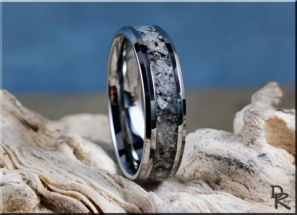 Tungsten ring with moonstone inlay resting on textured natural stone background by DR Rings
