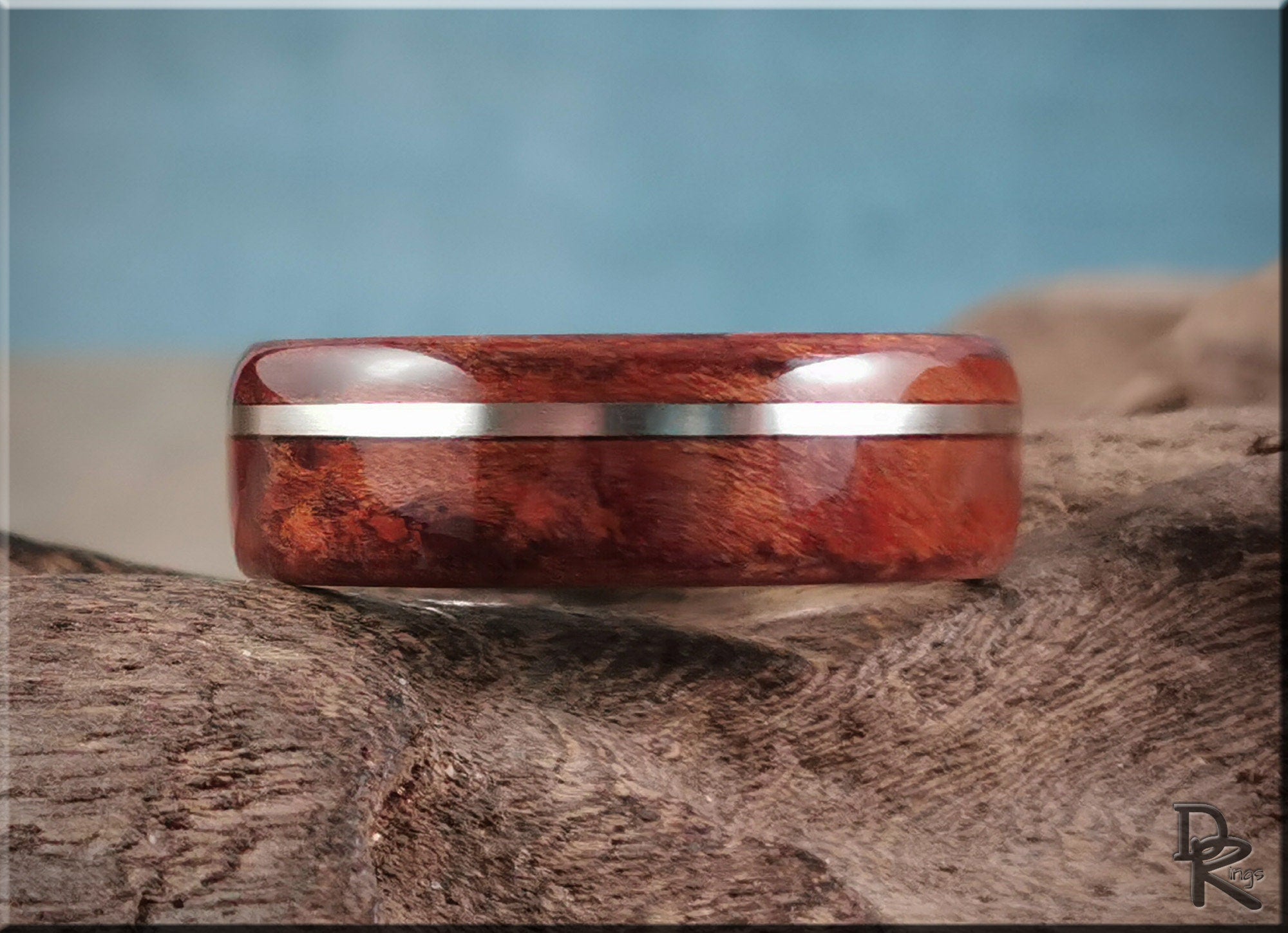 DR Rings redwood ring with inlay featuring polished wood and metal band on a textured surface