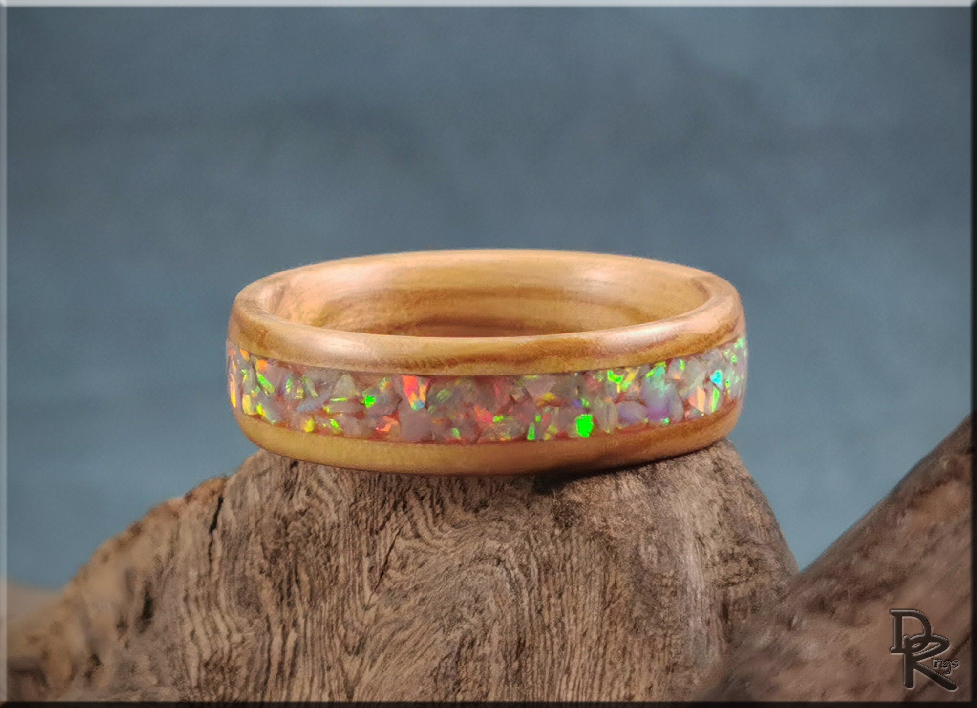 Wooden ring opal with vibrant multicolor opal inlay on a natural wood background