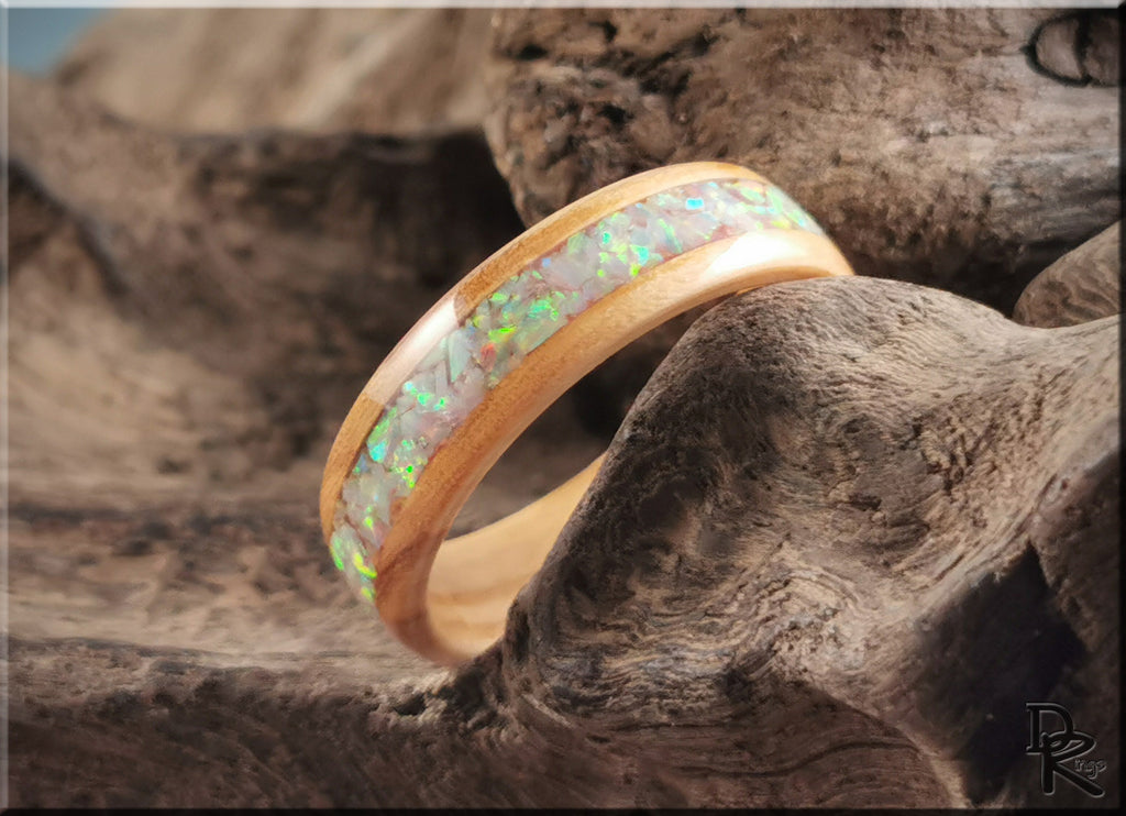 DR Rings wooden ring opal with iridescent inlay resting on textured natural wood