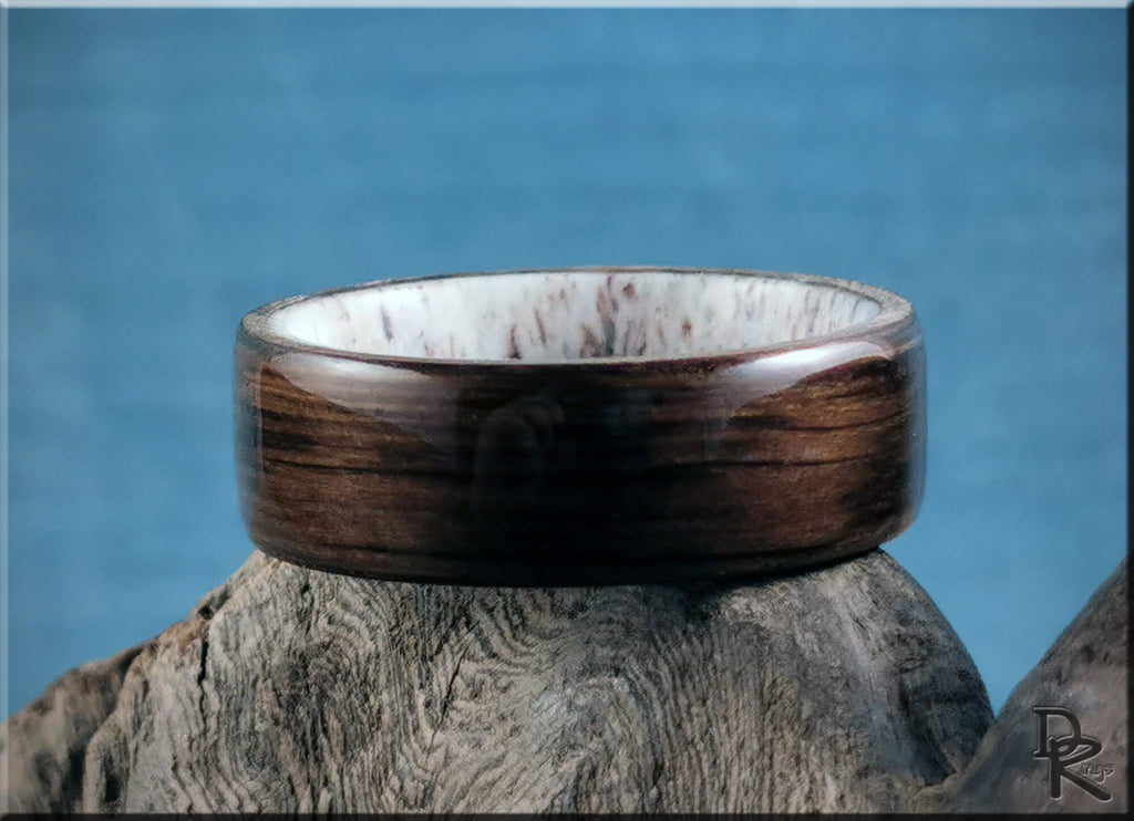 Dark brown bog oak wooden ring with smooth finish displayed on rustic wood by DR Rings