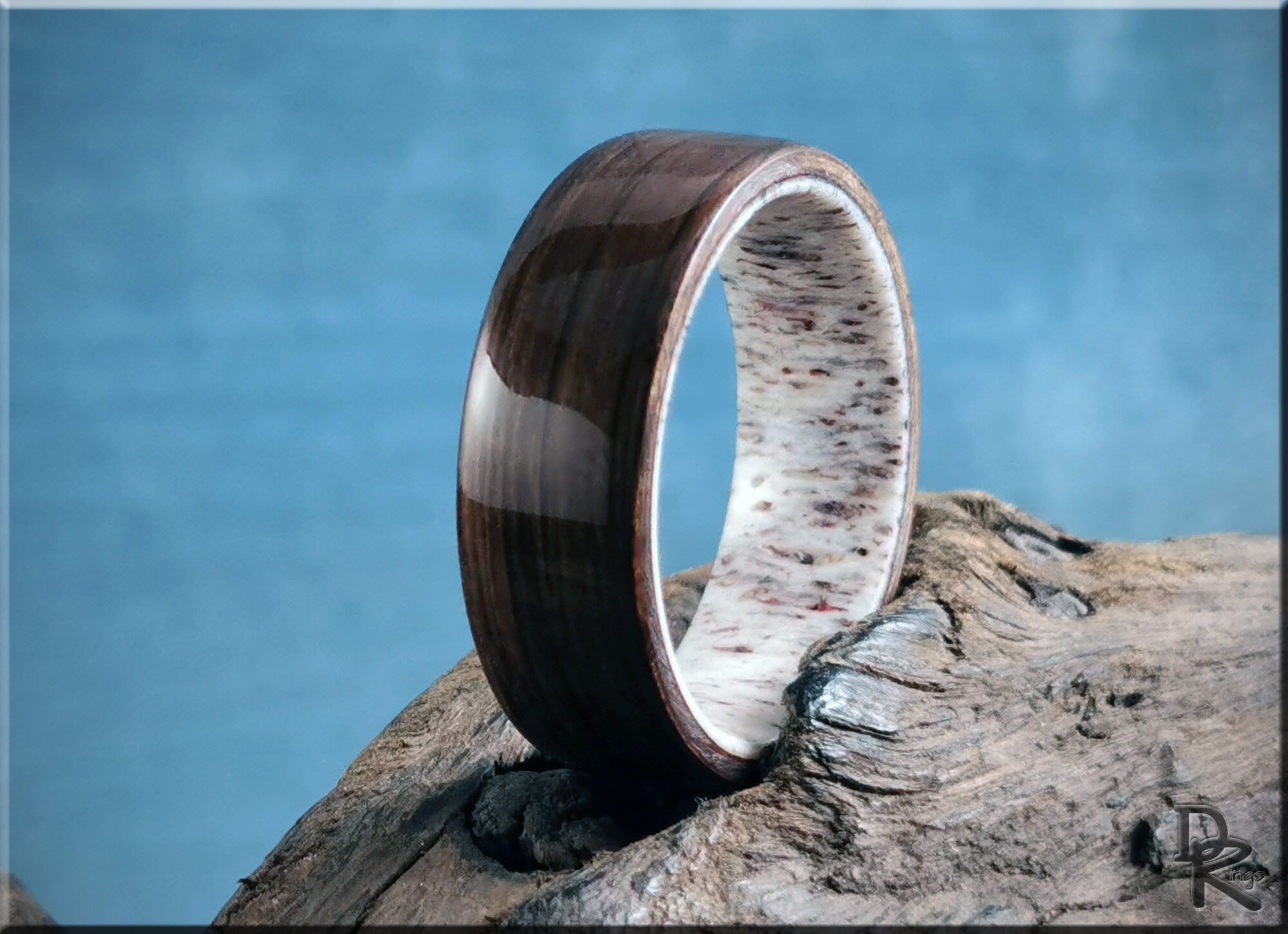 DR Rings polished dark bog oak wood ring with white speckled inner band on rustic wood background