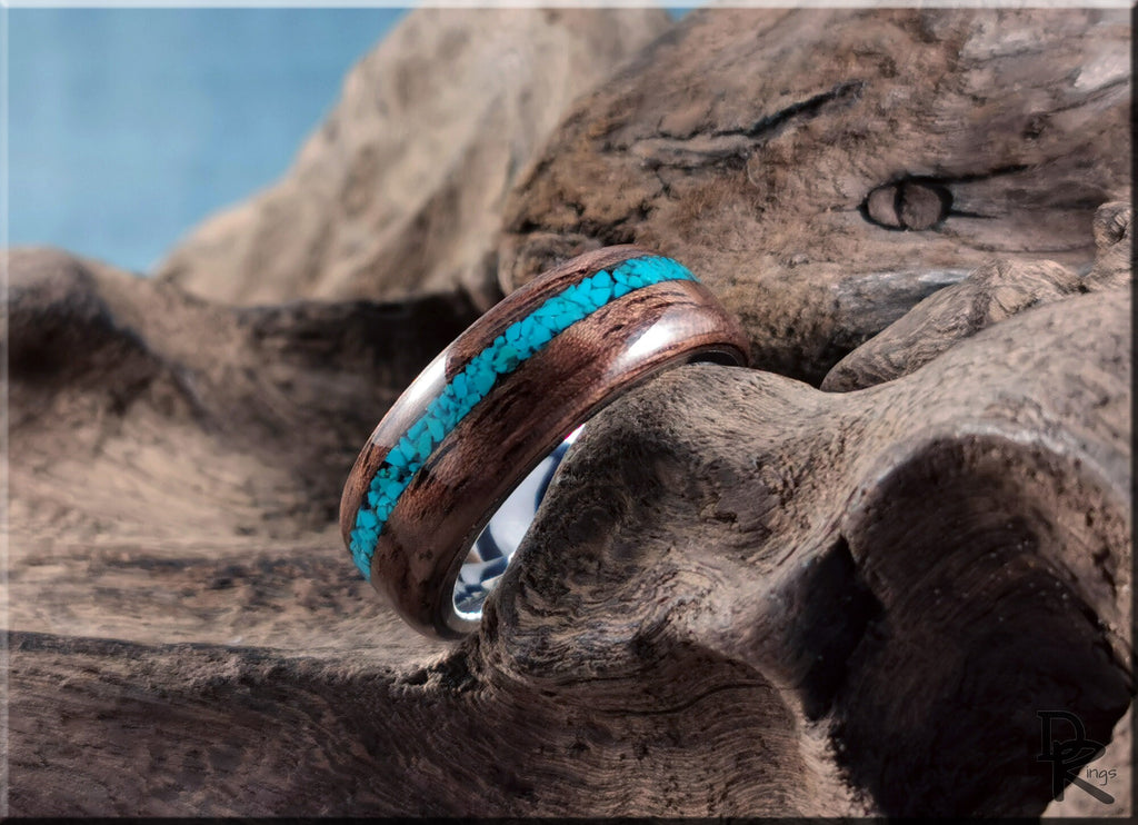 DR Rings walnut ring with turquoise inlay resting on textured natural wood surface