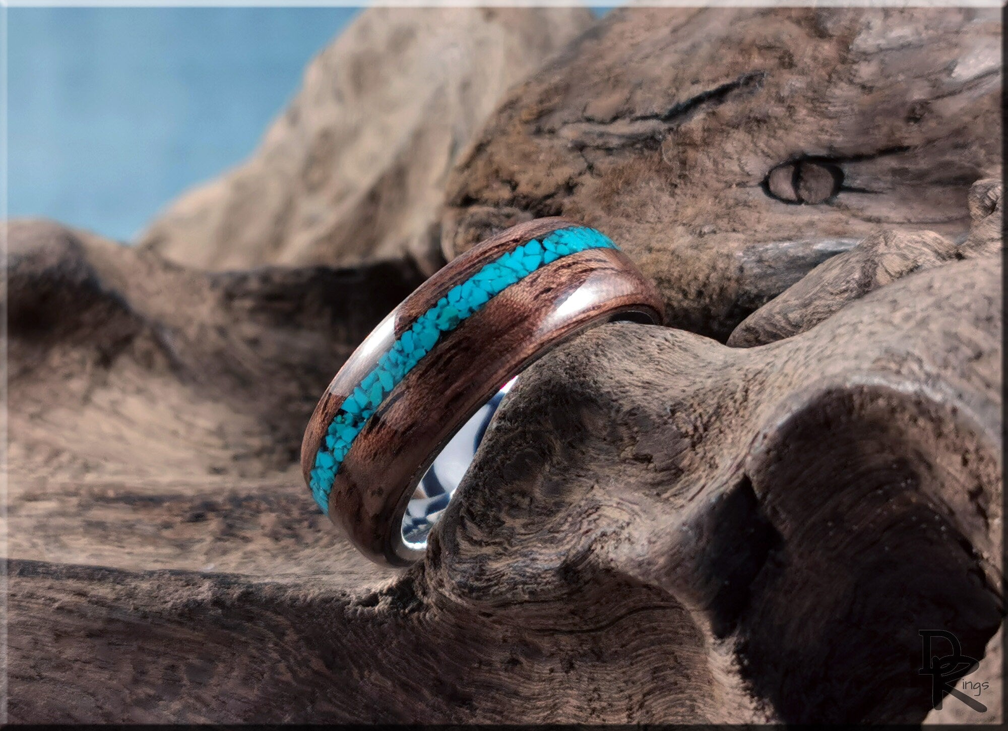 DR Rings walnut ring with turquoise inlay resting on textured natural wood surface