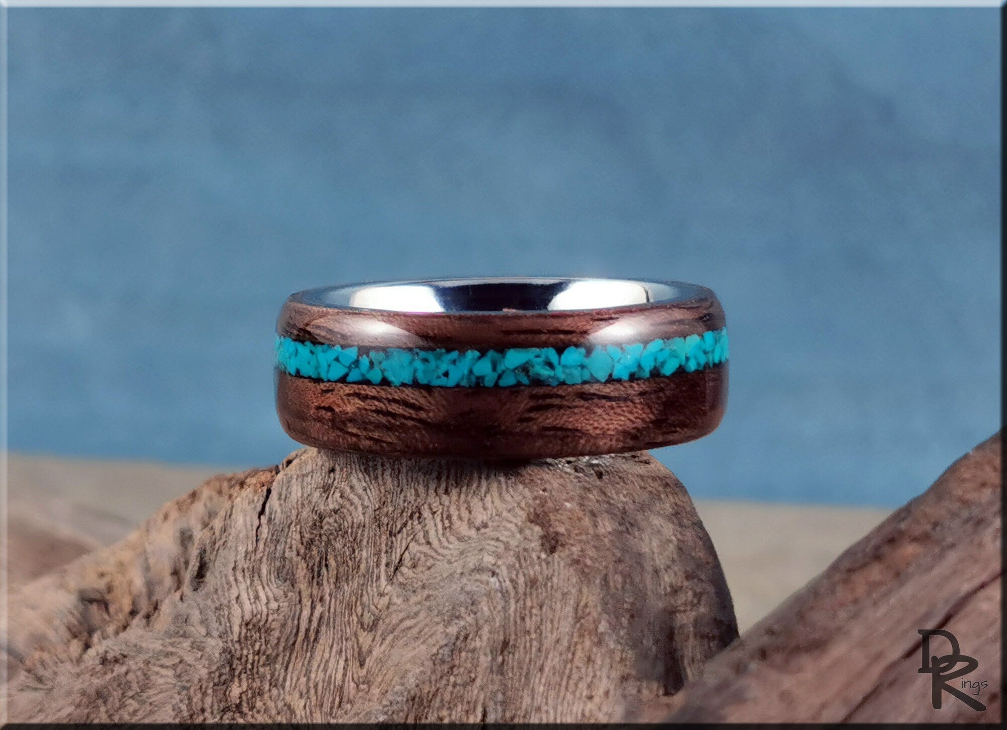 Walnut ring with turquoise inlay by DR Rings displayed on rustic wood with blue background