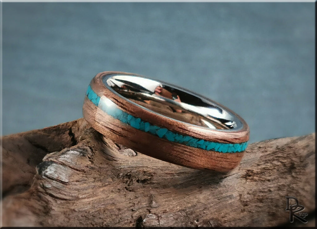 Walnut ring with turquoise inlay and polished silver interior displayed on rustic wood