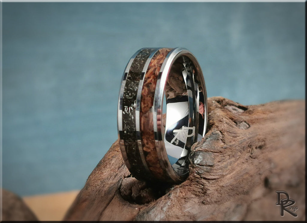 Tungsten ring with inlays featuring wood and dark stone accents by DR Rings on rustic wood background