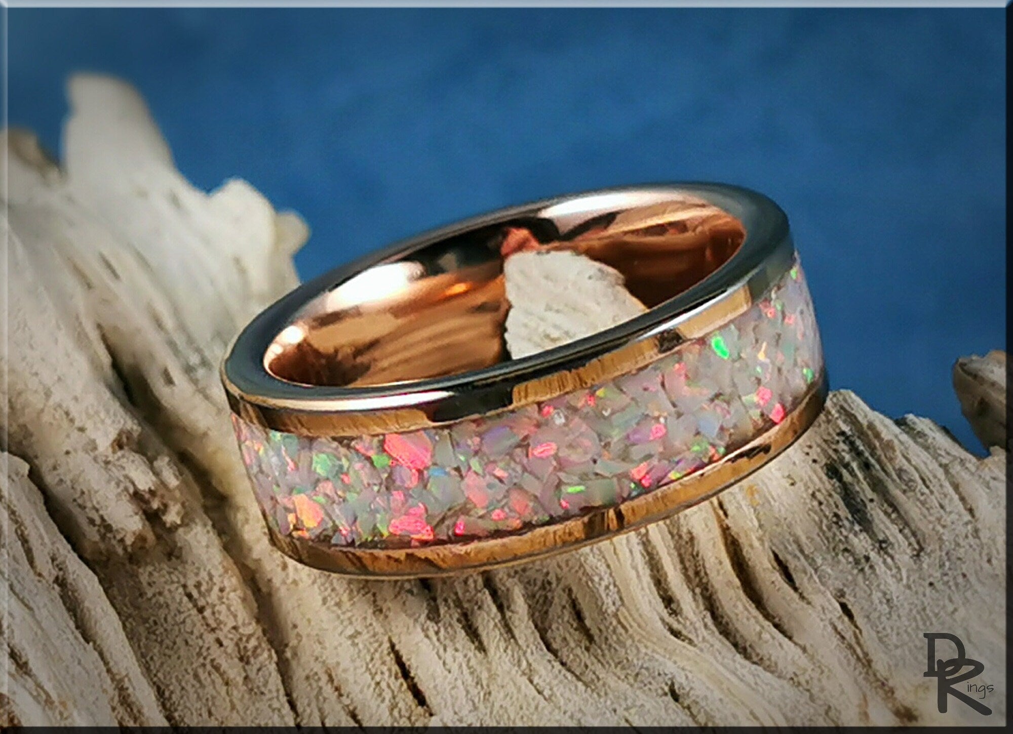 Rose gold ring with opal inlay featuring multicolor opal fragments on a textured background