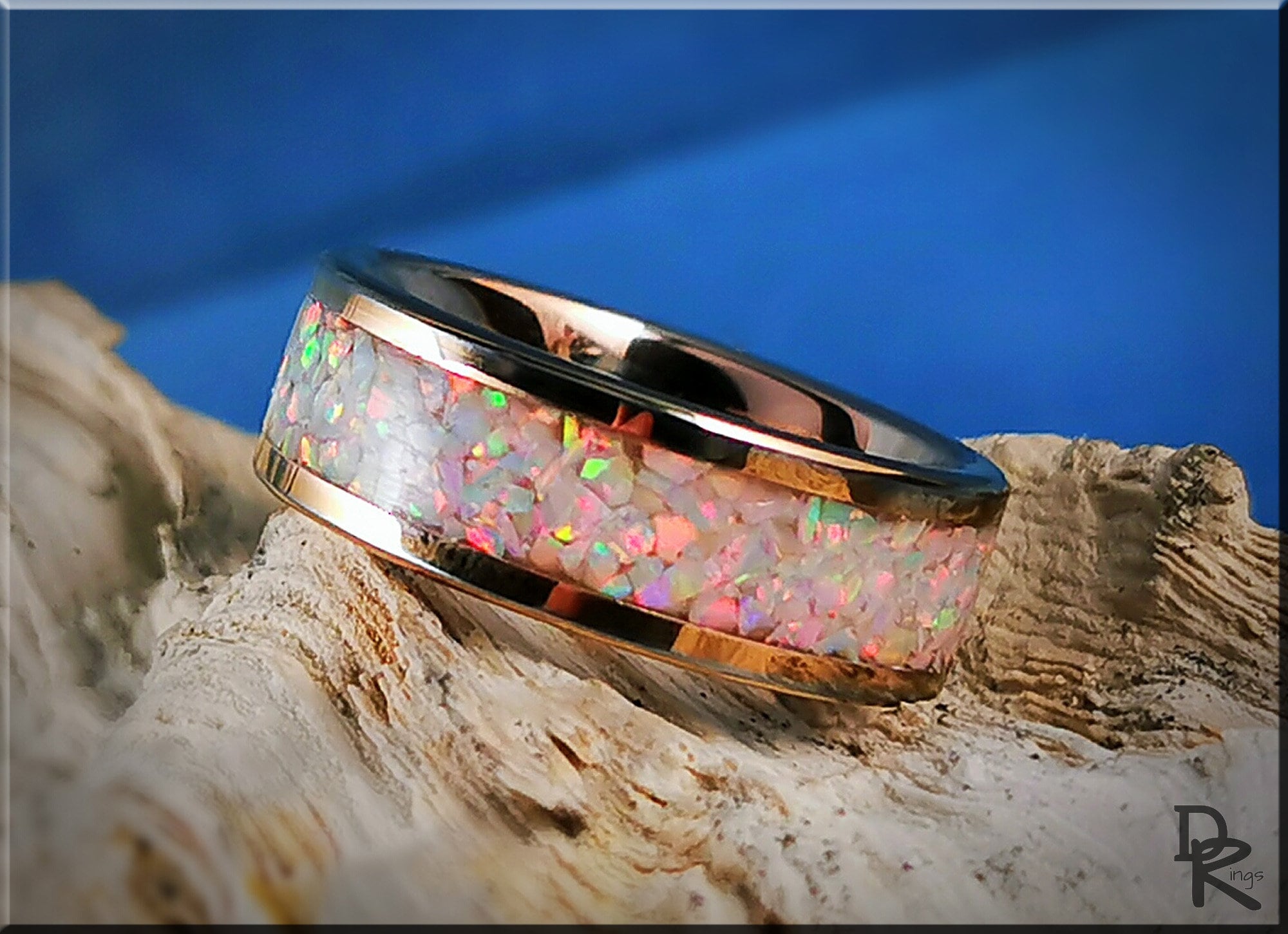 Rose gold ring with opal inlay reflecting colorful hues on textured wood surface