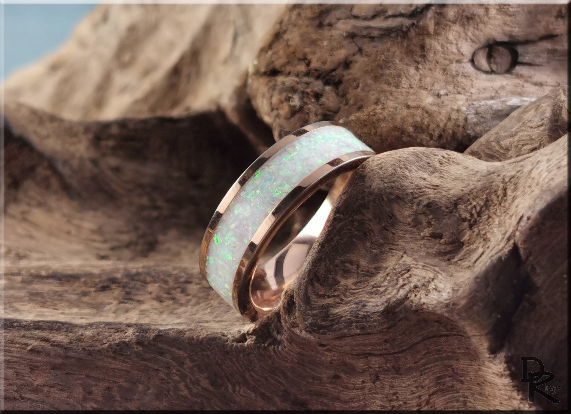 Rose tungsten ring with glow inlay featuring a polished rose gold finish on textured wood background
