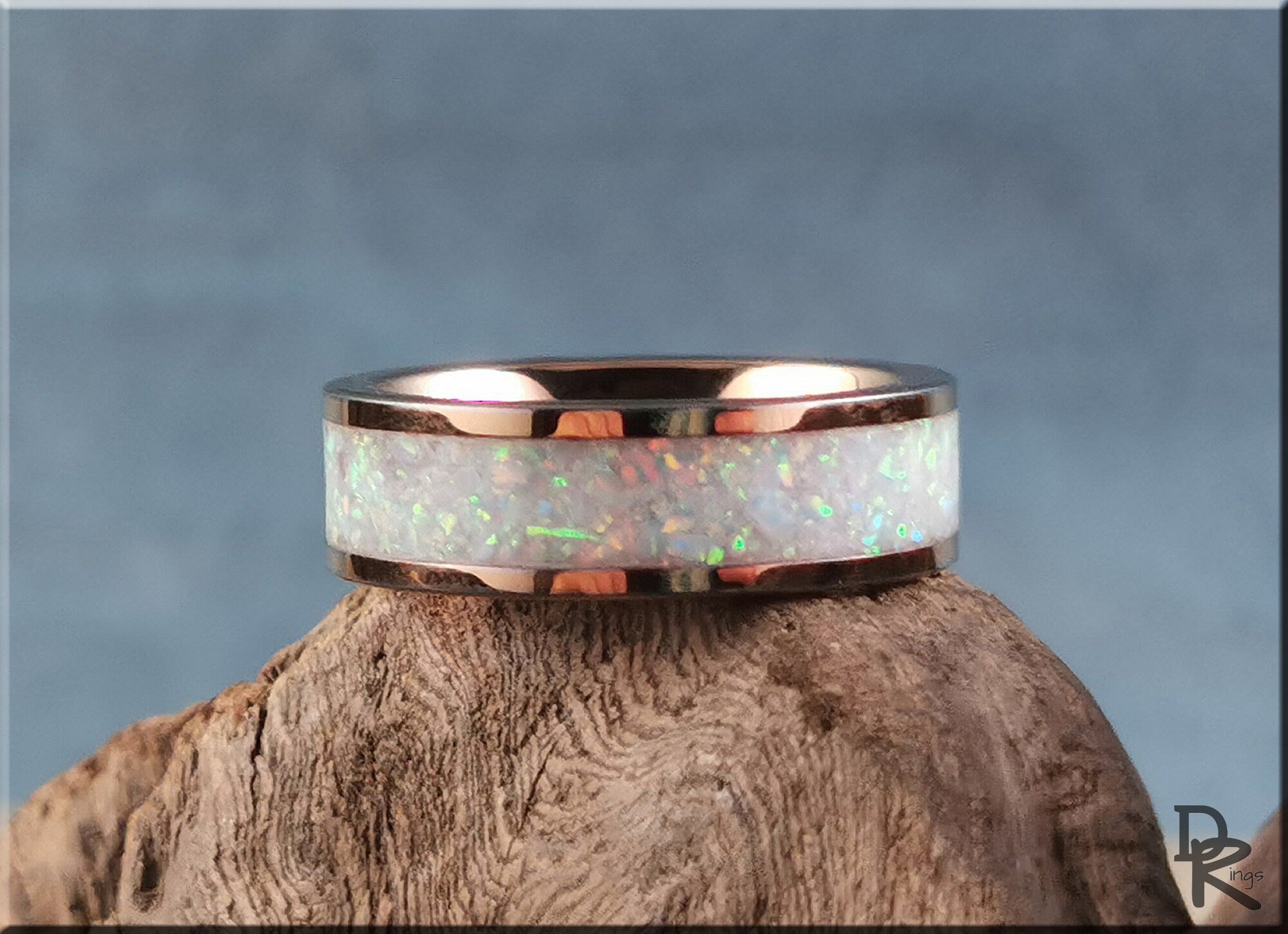 Rose tungsten ring with glow inlay featuring iridescent opal design on a wood background