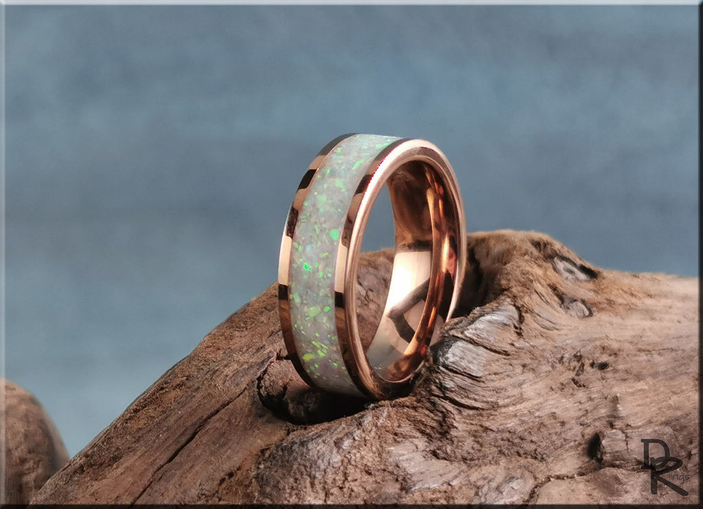 Rose tungsten ring with glow inlay featuring a vibrant green glow set on a wooden surface