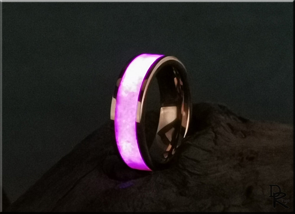 Rose tungsten ring with glow inlay glowing purple on a dark textured surface