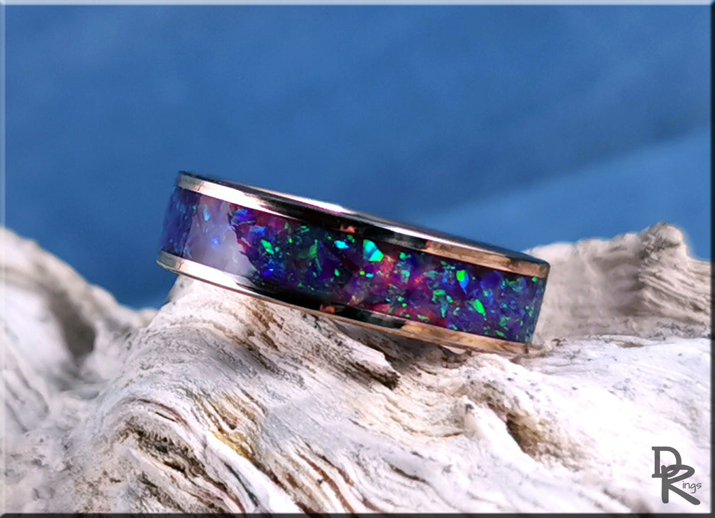 DR Rings rose tungsten ring with opal inlay featuring vibrant blue and green colors on textured background