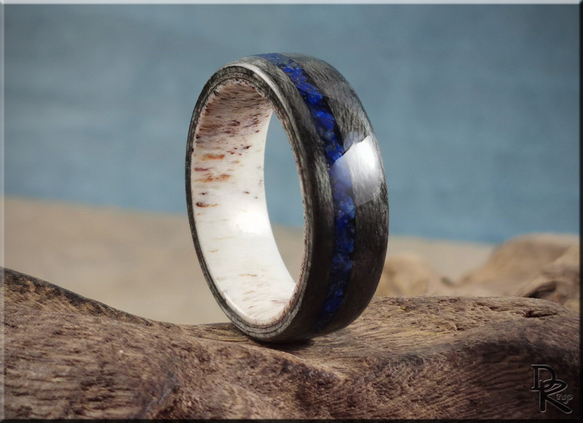 DR Rings carbon fiber ring with lazuli lapis inlay and white wooden interior on rustic wood background