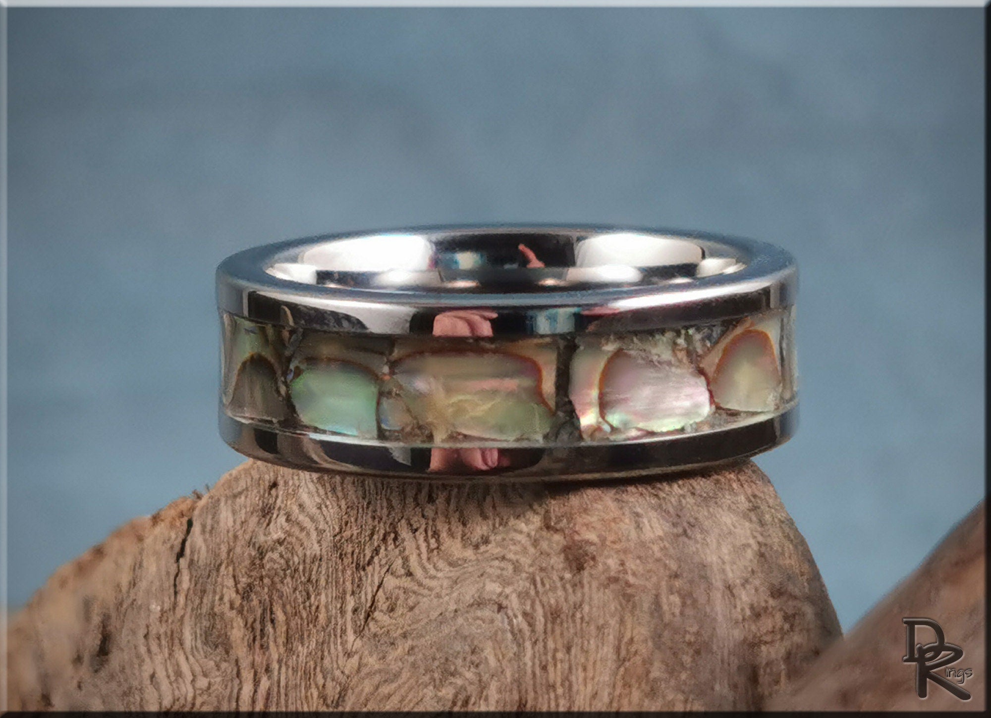 DR Rings super titanium ring with iridescent inlay on a rustic wooden surface