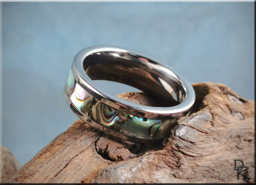 Super titanium ring with abalone shell inlay on a rustic wooden surface by DR Rings