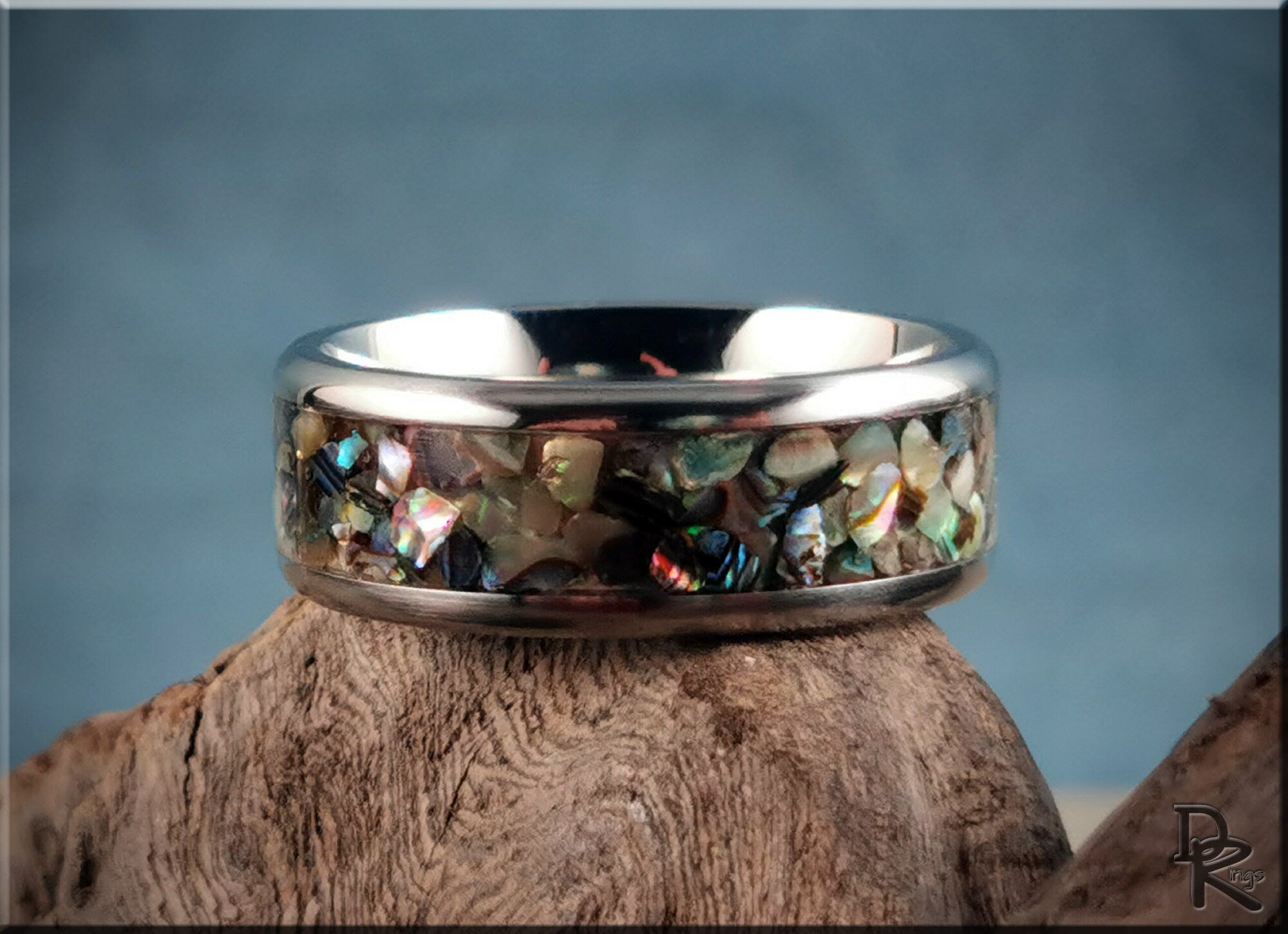 DR Rings titanium ring with abalone inlay on natural wood surface with blue background