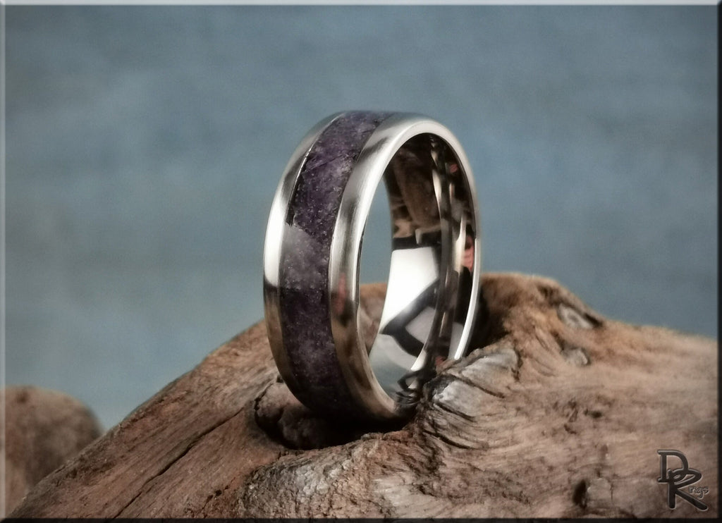 Titanium ring with amethyst inlay resting on rustic wooden surface with polished finish