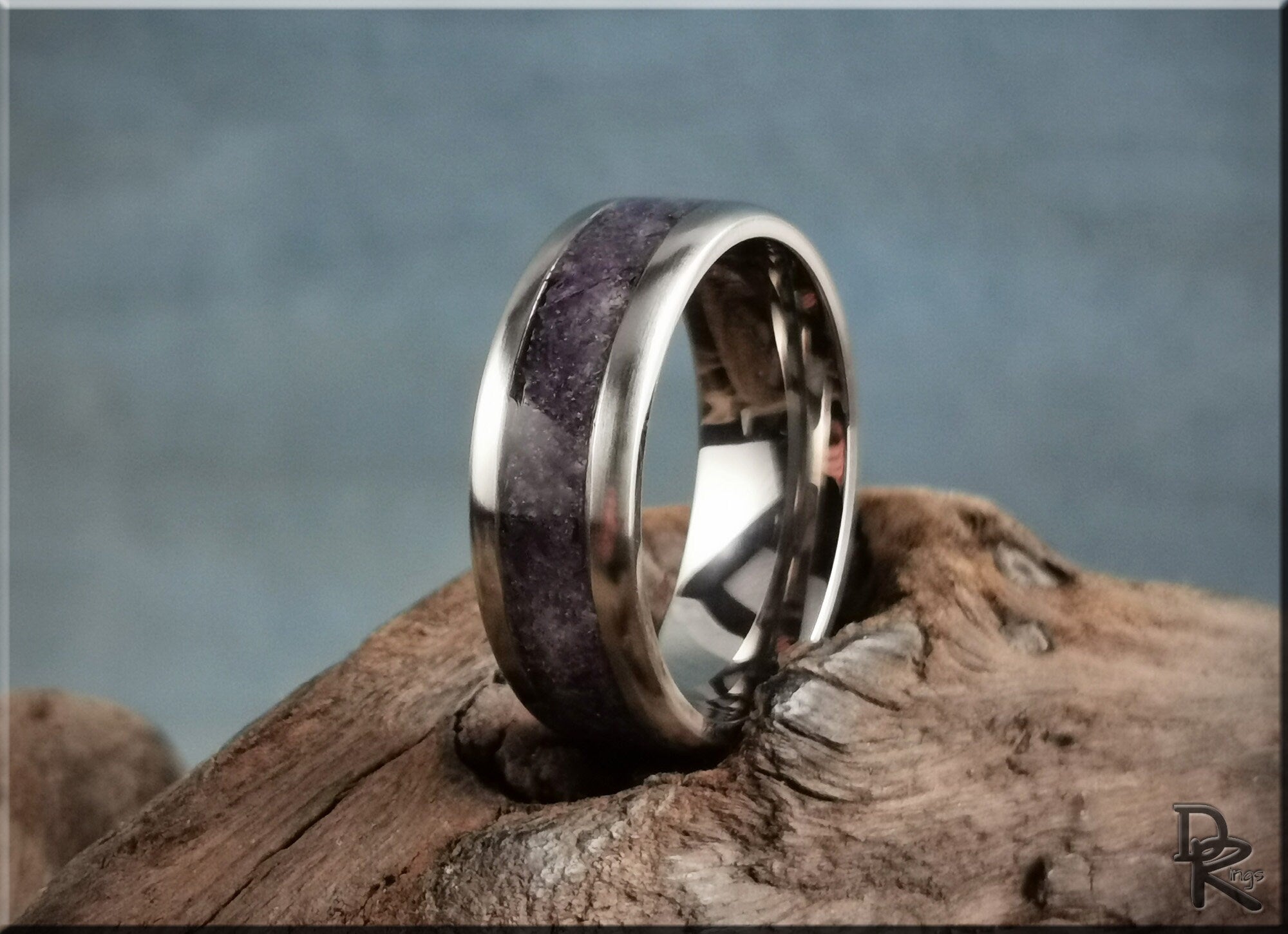 Titanium ring with amethyst inlay resting on rustic wooden surface with polished finish