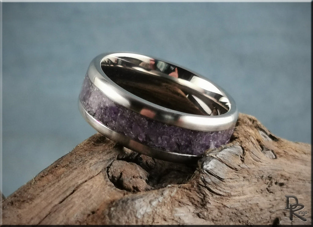 Titanium ring with amethyst inlay resting on textured wood surface by DR Rings