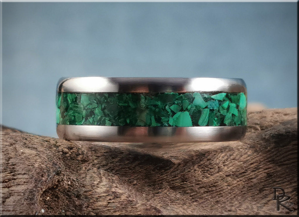 Titanium ring with malachite inlay showing vibrant green stones set in a polished metal band