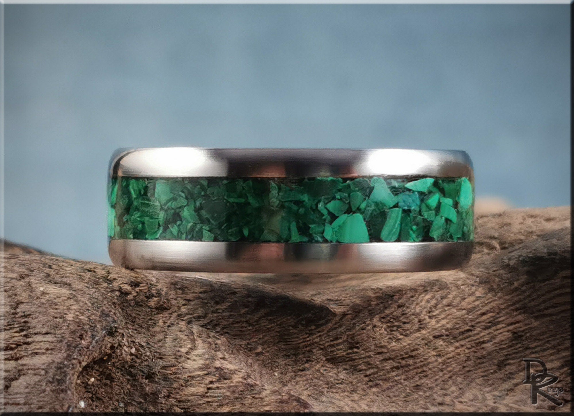 Titanium ring with malachite inlay showing vibrant green stones set in a polished metal band