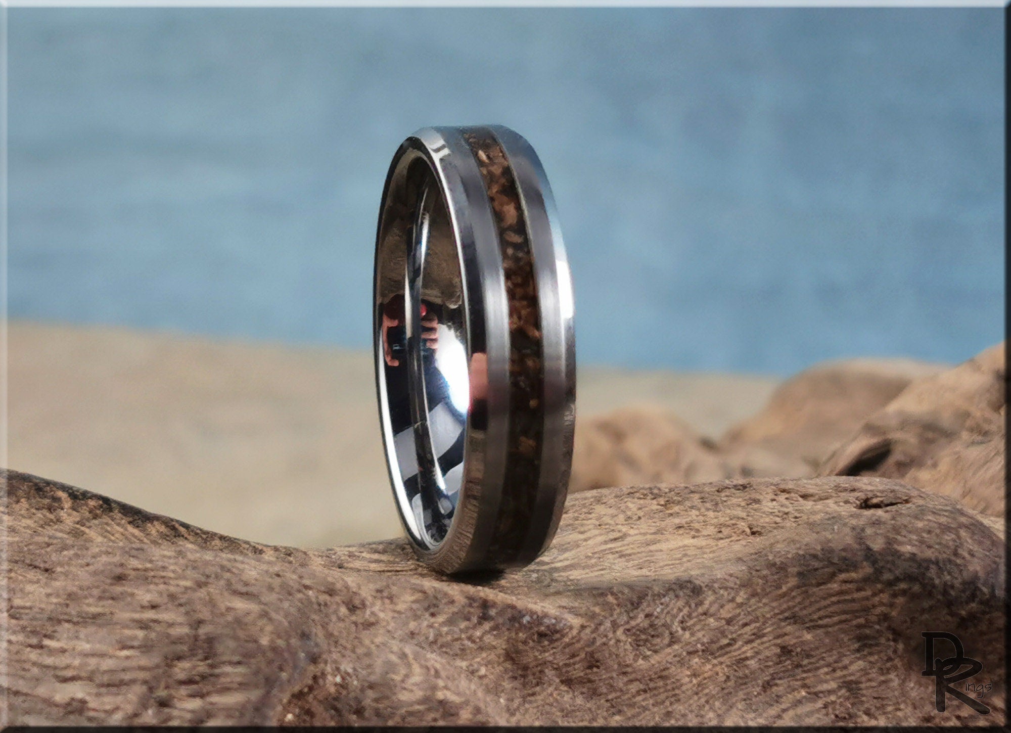 Tungsten carbide ring with inlay featuring a dark wood design from DR Rings on natural textured background