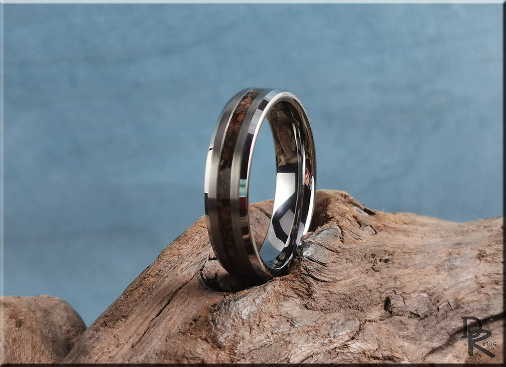 DR Rings tungsten carbide ring with inlay featuring a polished dark wood design on a rustic wooden surface