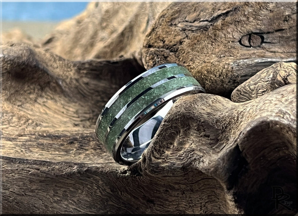 Tungsten ring carbide with emerald inlay featuring polished silver edges on rustic wood background