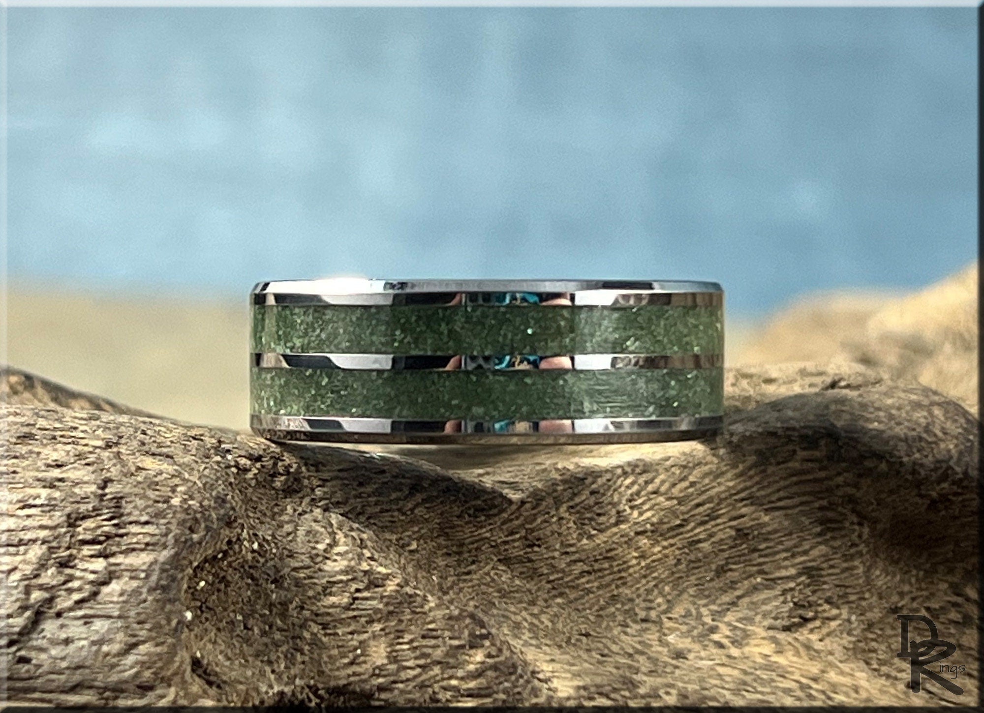 DR Rings tungsten ring carbide with emerald inlaid design on textured wood background