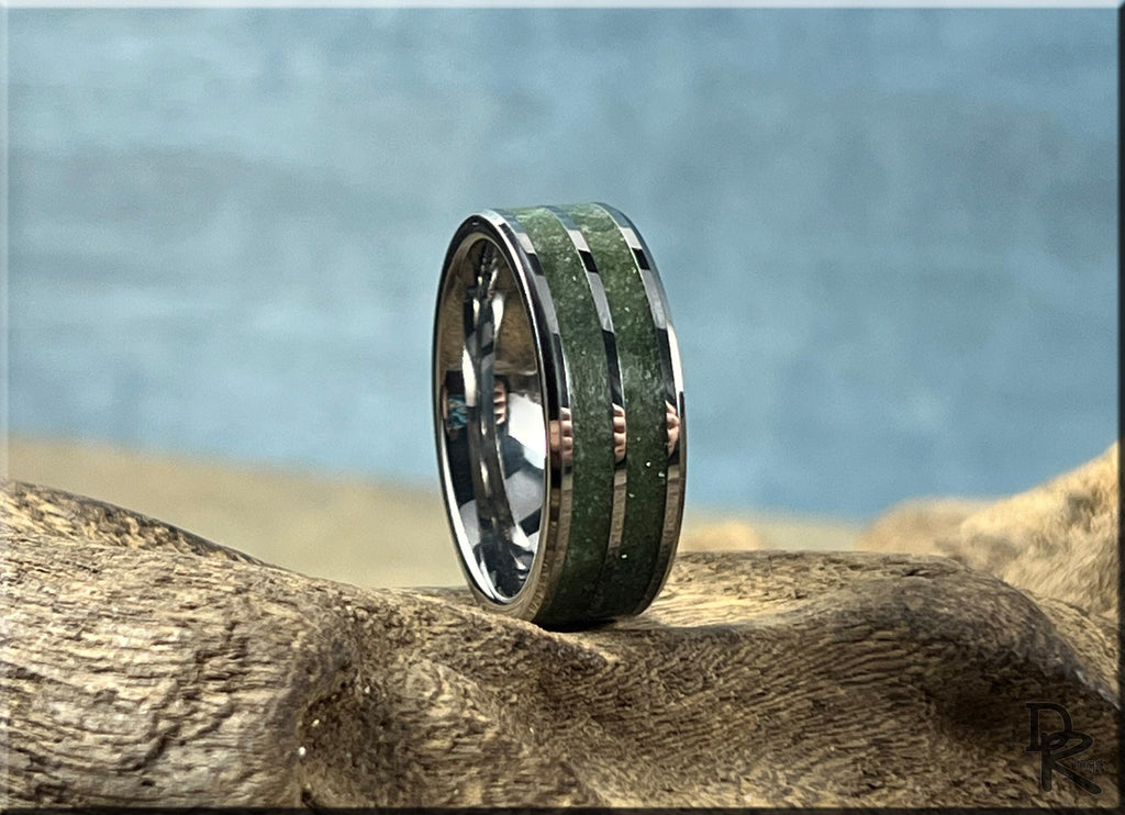 DR Rings tungsten ring carbide with emerald green inlay resting on textured wood surface