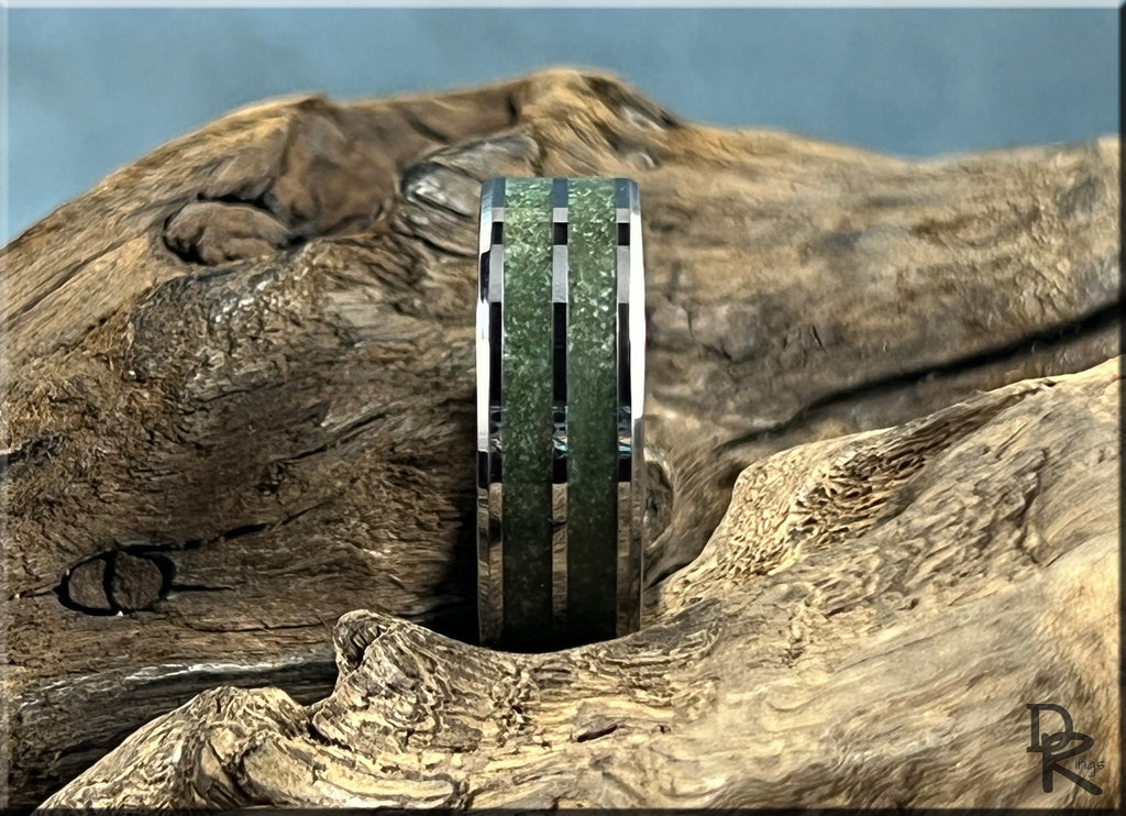 Tungsten ring carbide with emerald inlay set against textured natural wood background by DR Rings