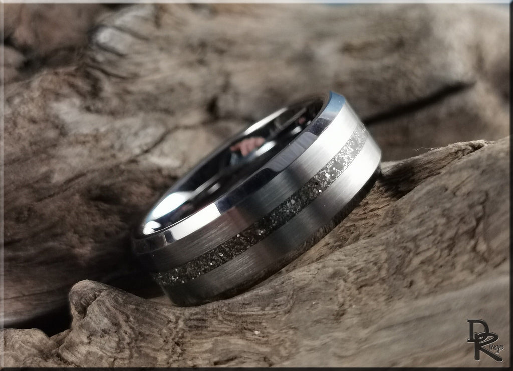 Tungsten ring with meteorite inlay resting on rustic textured wood background by DR Rings