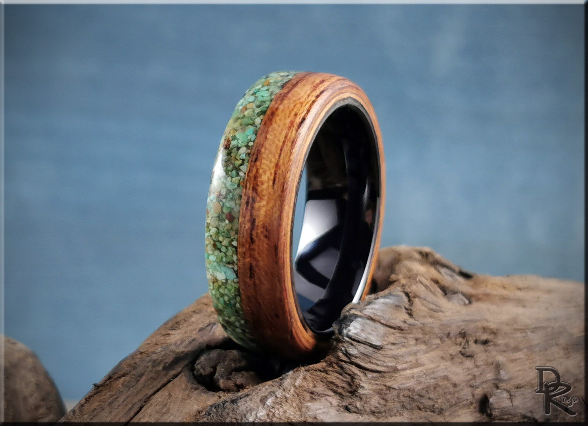 DR Rings handcrafted wood and stone turquoise inlay rings with polished black interior on a rustic wooden surface