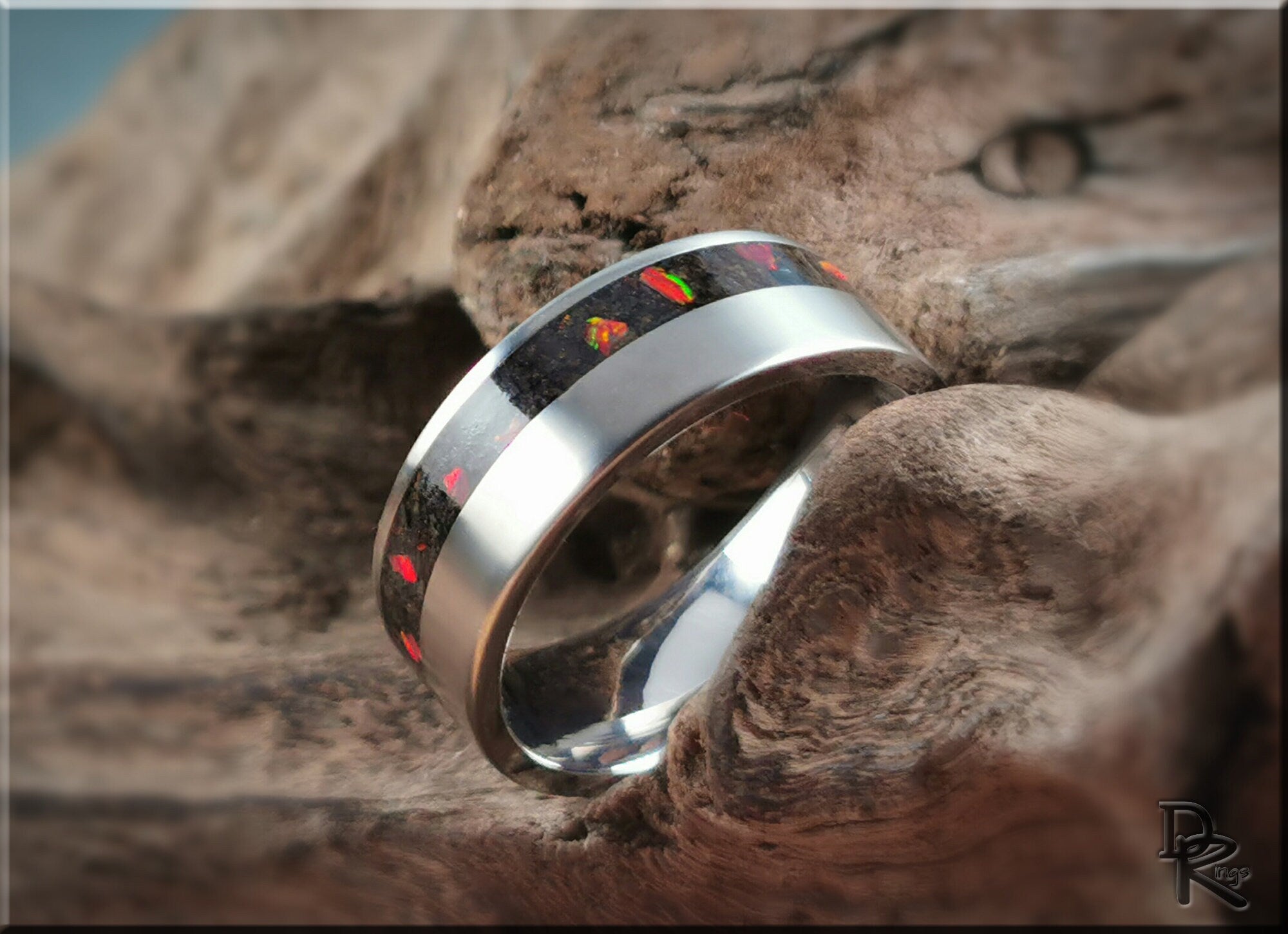 DR Rings titanium ring with inlay featuring a black and colorful pattern set on a rustic wooden background