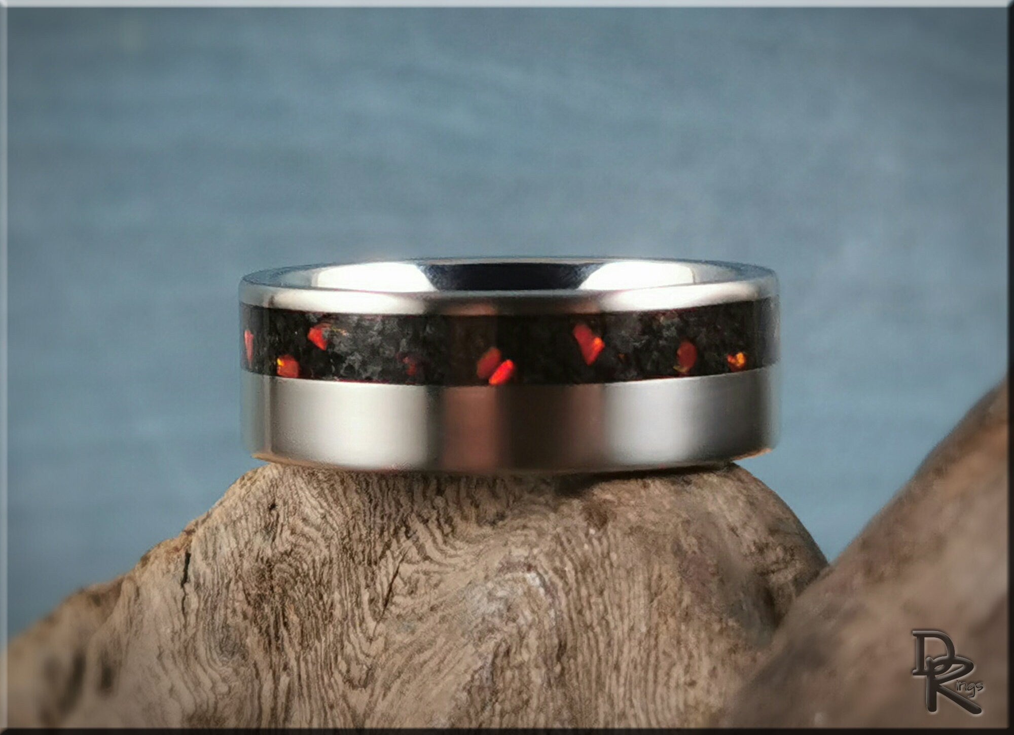 DR Rings titanium ring with inlay featuring red and black design on a natural wood background