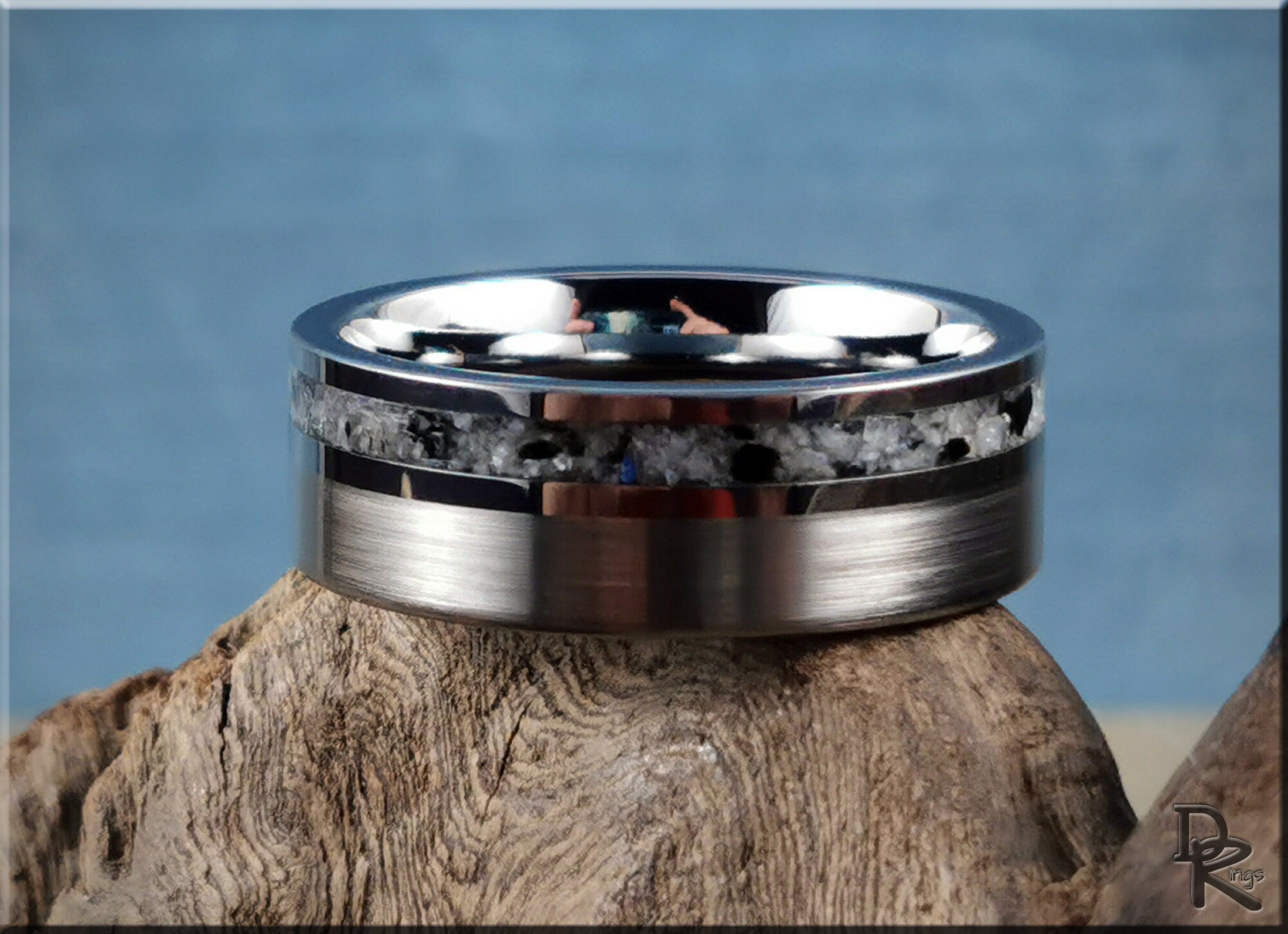 Tungsten carbide ring with moonstone inlay resting on natural wood background