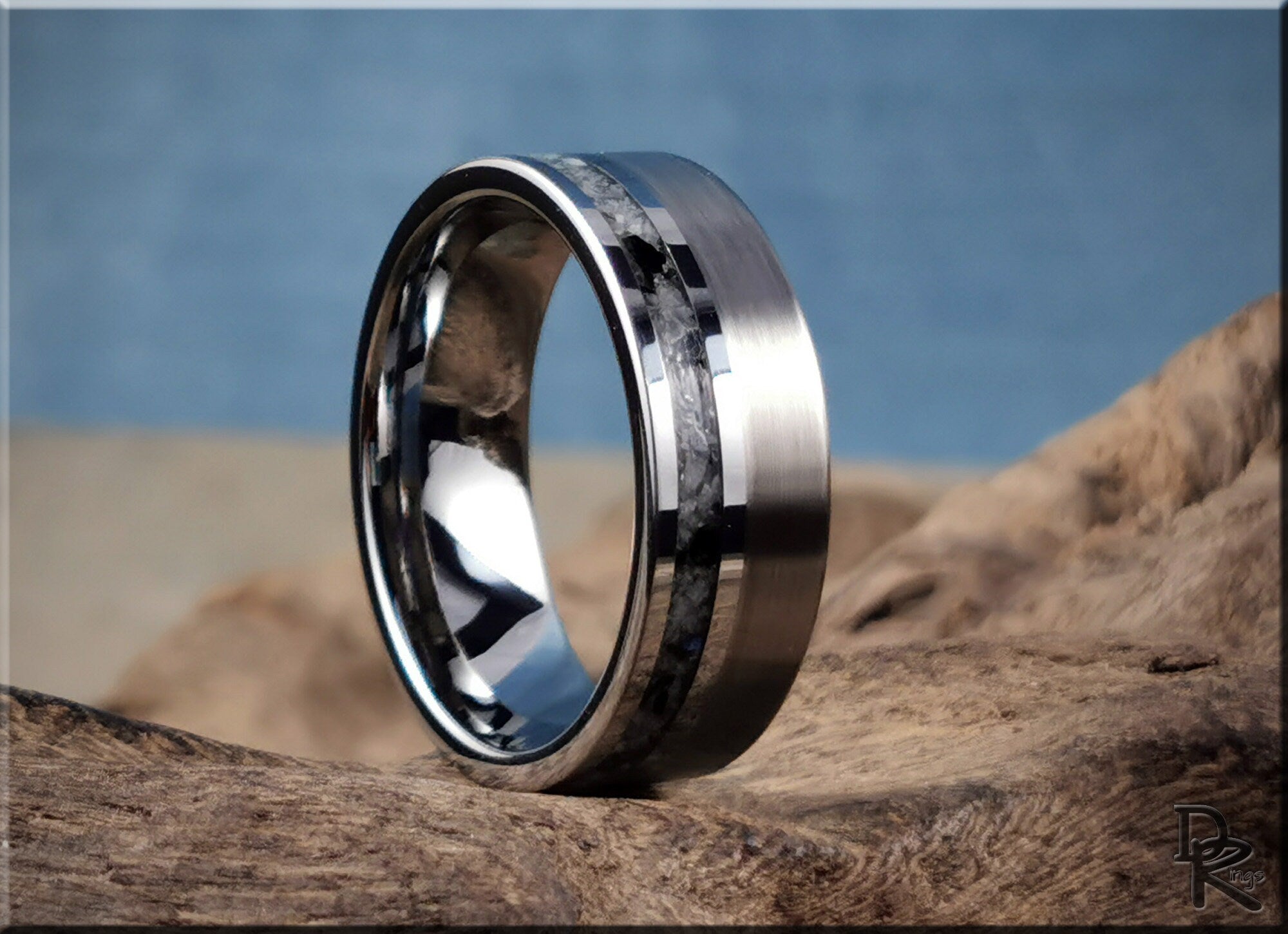 DR Rings tungsten carbide ring with moonstone featuring a polished black and silver design on rustic wood