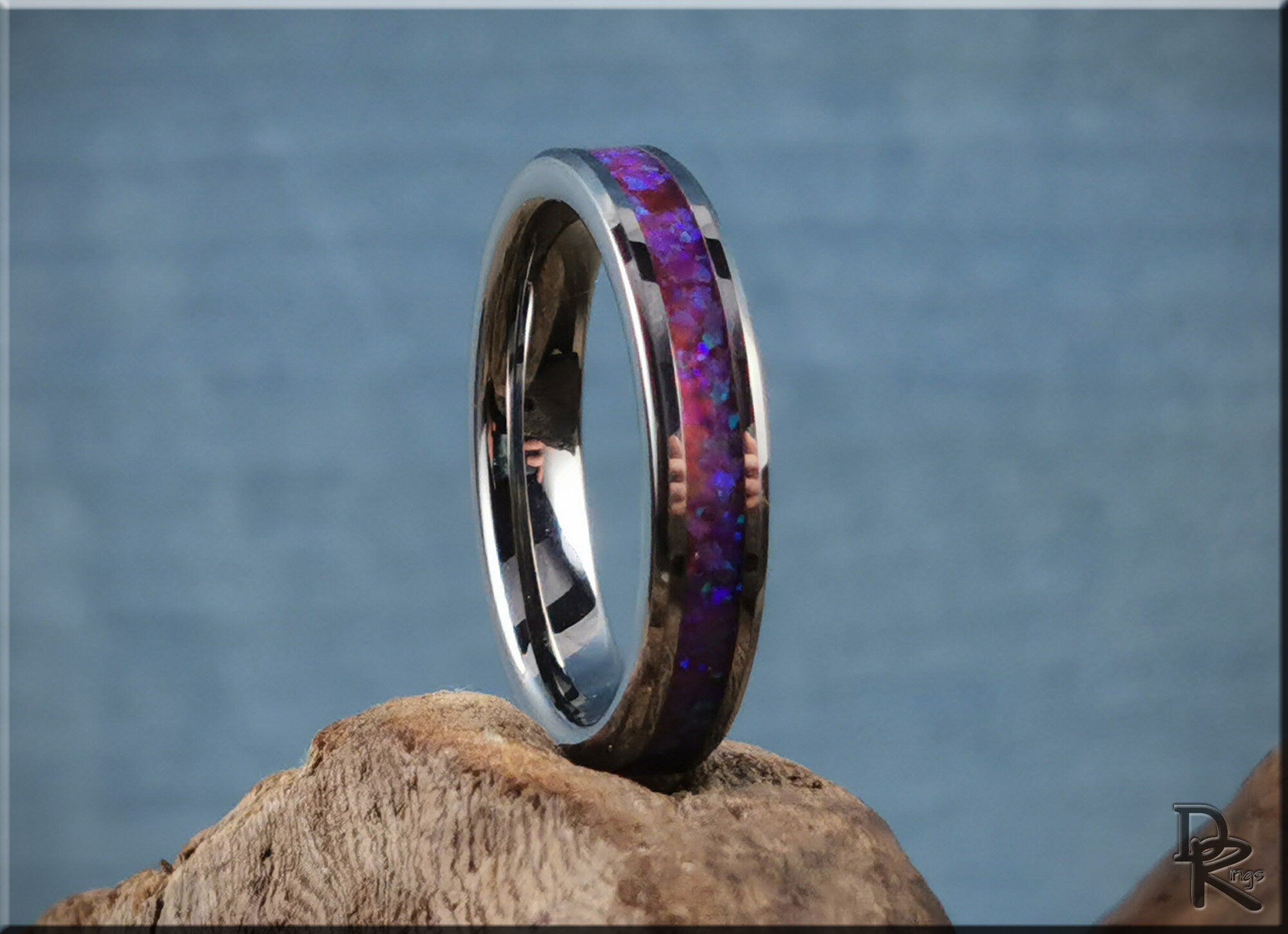 DR Rings tungsten carbide ring with opal inlay in purple hues on a natural wooden surface