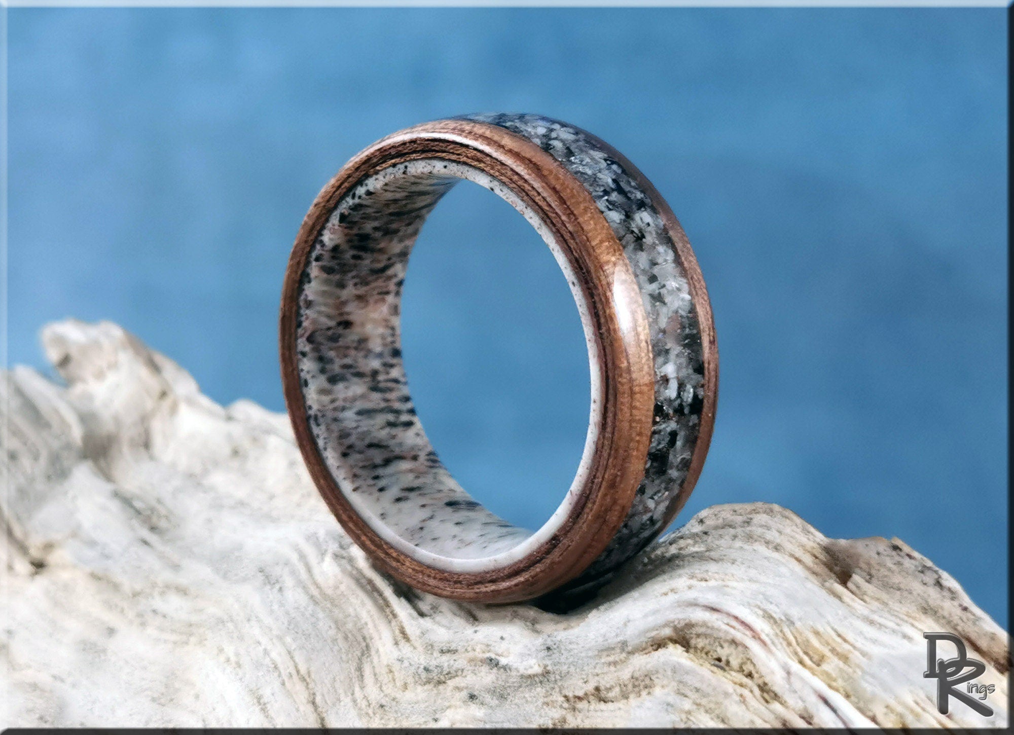 DR Rings walnut wood ring with with inlay on antler core on textured surface with blue background